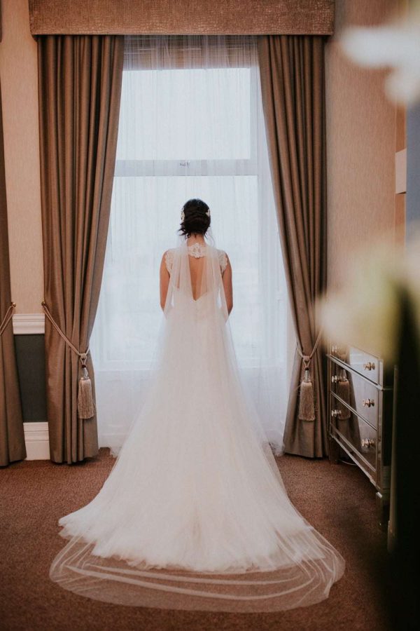 Pretty bride wearing a 1920s inspired chapel length drape veil in silk effect tulle