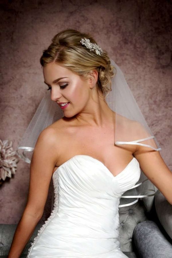 Close up of bride wearing pretty elbow length ribbon edge veil