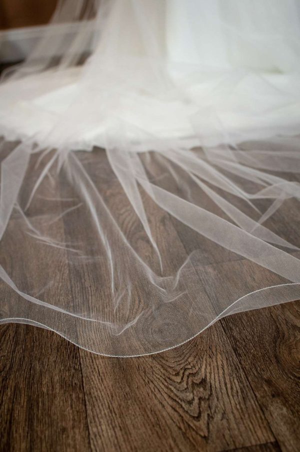 Isabella - one layer cathedral length extra wide veil with a wavy edge on a bride closeup bottom of train