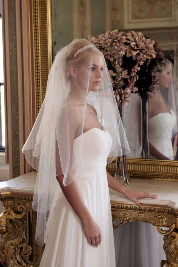 Bride in grand golden ballroom wearing a wedding veil over the face